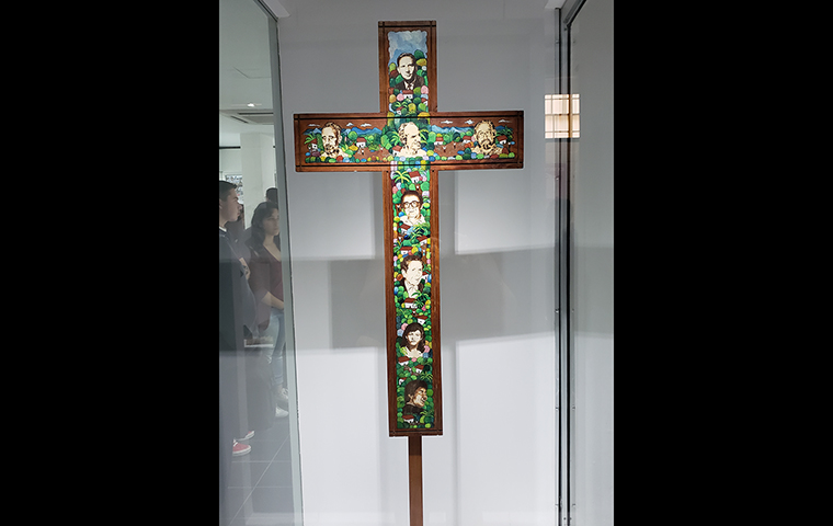A colorful cross is decorated with the faces of the eight massacre victims.