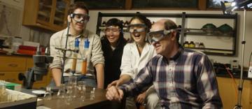 Four men posing together in a kitchen.