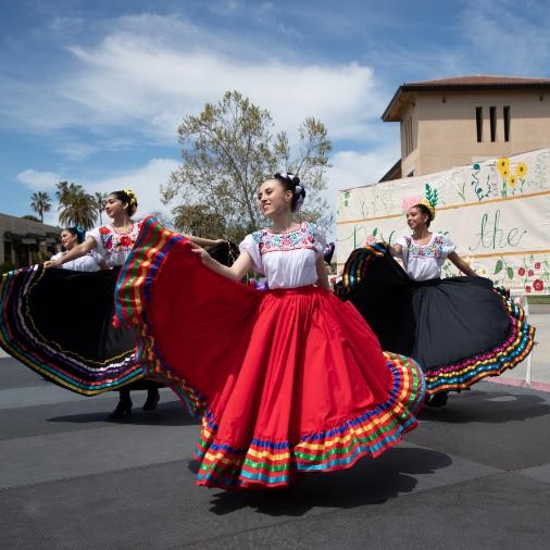 Three Folkorico dancers perform at a street fair 