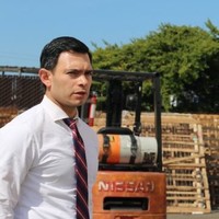 A person in a white shirt and tie outdoors near machinery.
