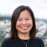 A person smiling with an urban background.