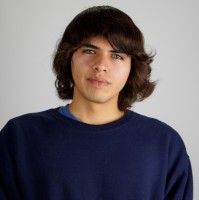 A person wearing a blue sweater against a plain background.