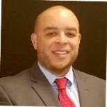 A person in a suit with a red tie smiling.