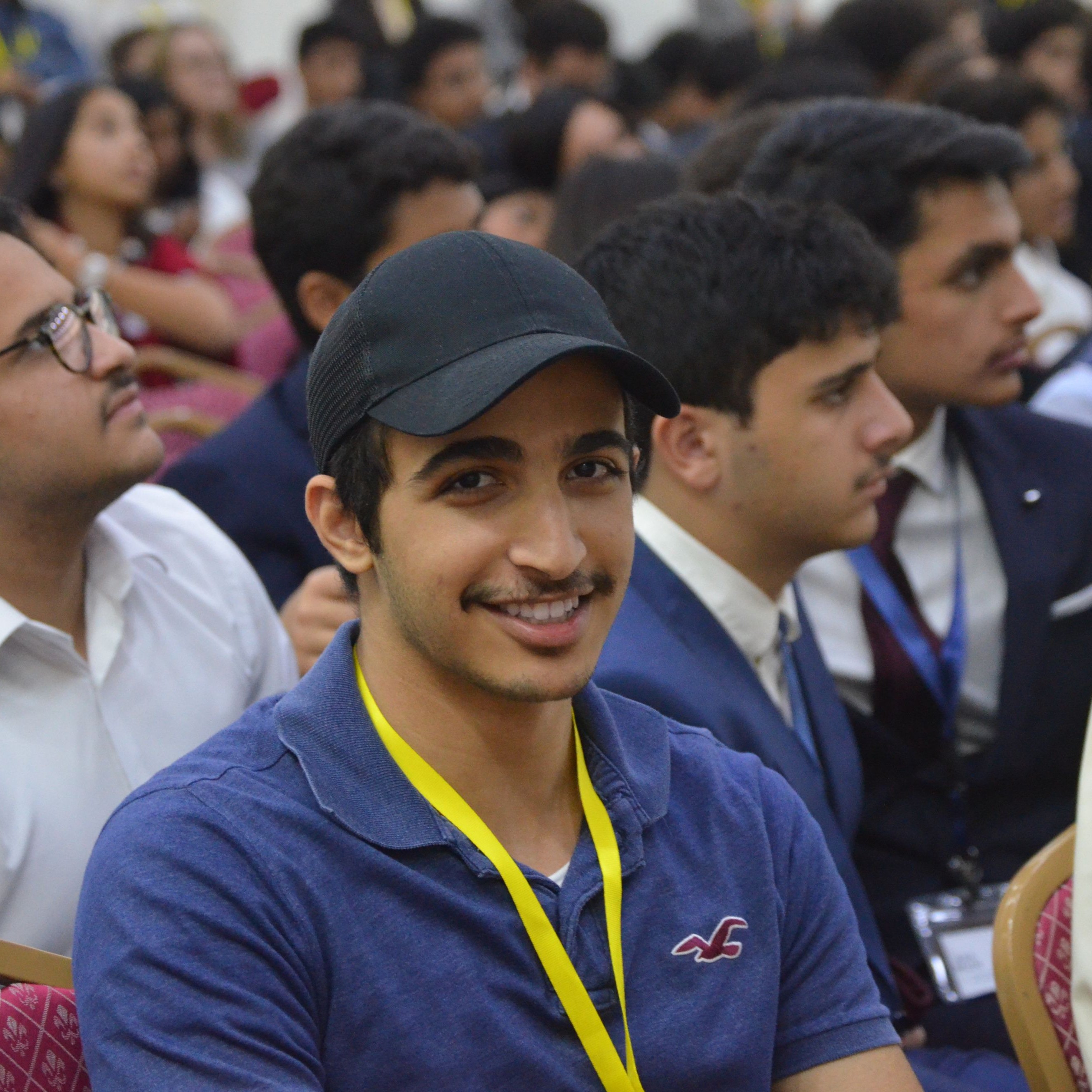 A person wearing a cap and lanyard at an event. 