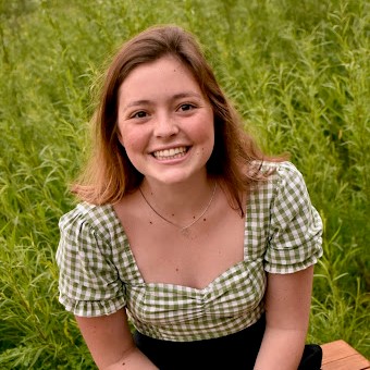 A person smiling in a green field. 