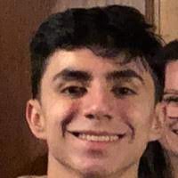 A person smiling with another person's partial face visible in the background.