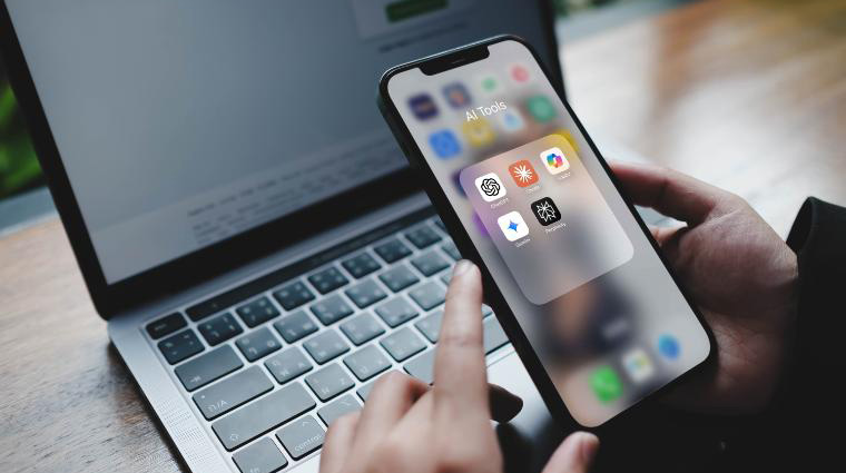 A phone with AI apps being held in front of a laptop.