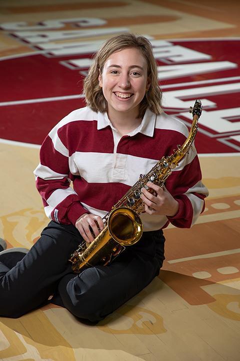 A person sitting on the floor with a violin, smiling.
