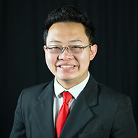 A person smiling in a suit with a red tie.