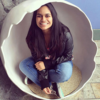 A person smiling while sitting inside a circular structure.