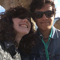 Two people wearing sunglasses smiling for a photo outdoors.