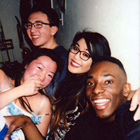 Four smiling people posing for a photo together indoors.