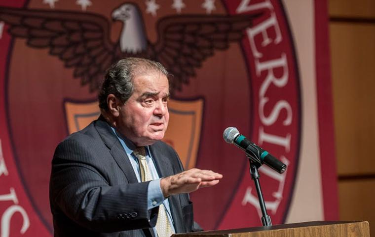 Antonin Scalia speaking at a university event behind a podium and microphone. image link to story