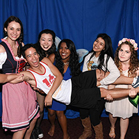 A group of people in costumes posing in front of a blue backdrop.