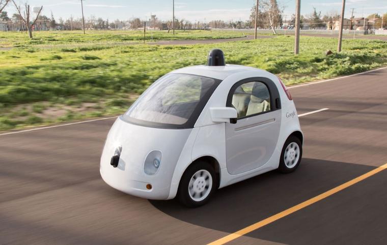 A self-driving car on a paved road with a grassy background. image link to story