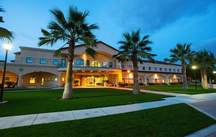 Night view of Vari Hall with palm trees and lit pathways. image link to story