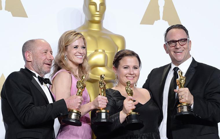 Four people holding Oscars, standing in front of a golden statue. image link to story