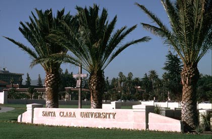 Santa Clara University is written on a sign at campus entrance surrounded by palm trees. image link to story