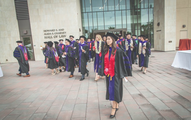 Law graduates in gowns on Charney Hall entrance patio