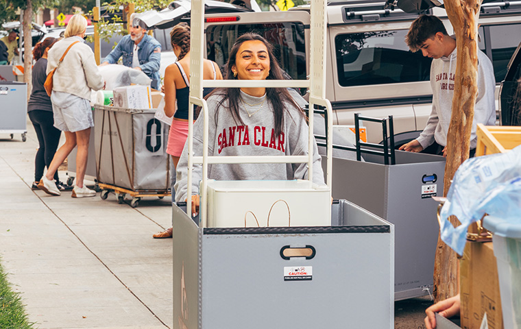 Student smiling pushing a mve-in cart on Welcome Weekend
