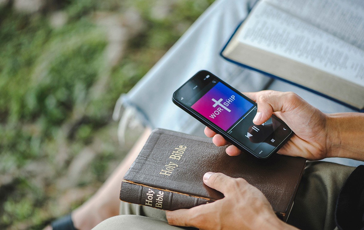 Hands holding phone and closed Bible on lap