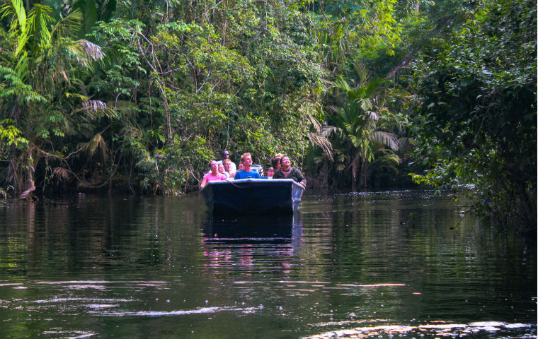 SCU students on a boat in Toruguero, Costa Rica, surrounded by lush green trees. 