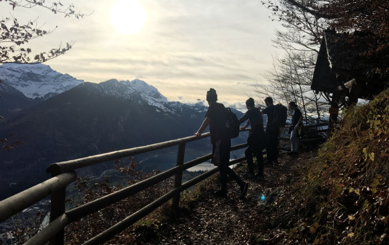 Silhouette of student hikers overlooking a fence at a peak of Handerkulm Mountain