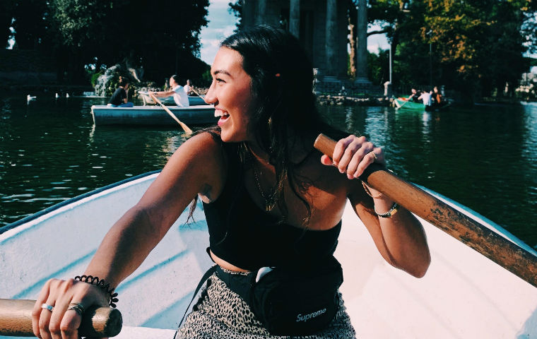 Student Kaitlin Alayo rowing a boat in Rome, Italy, looking backwards and smiling