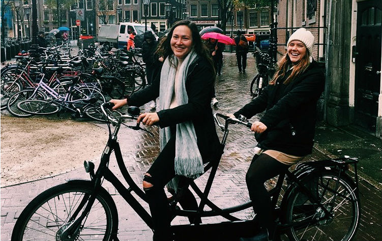 Students Kendra Bean and Maggie Oys on a two-seater bicycle in Amsterdam