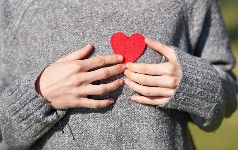 Closeup of student's grey sweater holding up a felt heart.