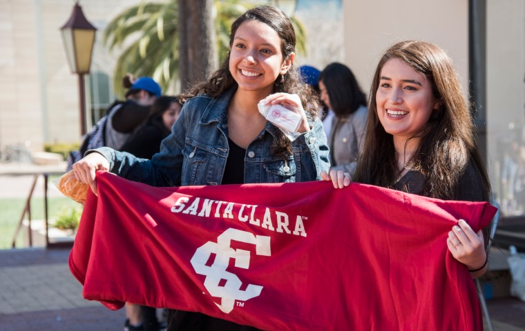 Two students outside Benson holding a red banner with SCU logo