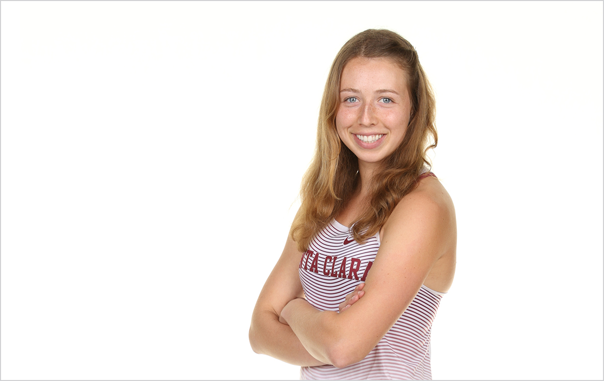 Hope Olbricht in her cross country jersey in front of a white backdrop, standing arms crossed.