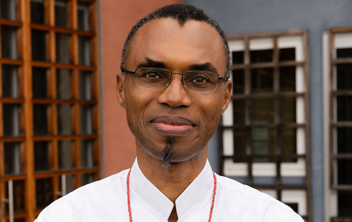 A black man with glasses and a white shirt looks at the camera.