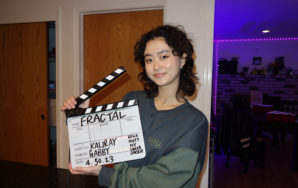 A student holds a clap board on a film set.