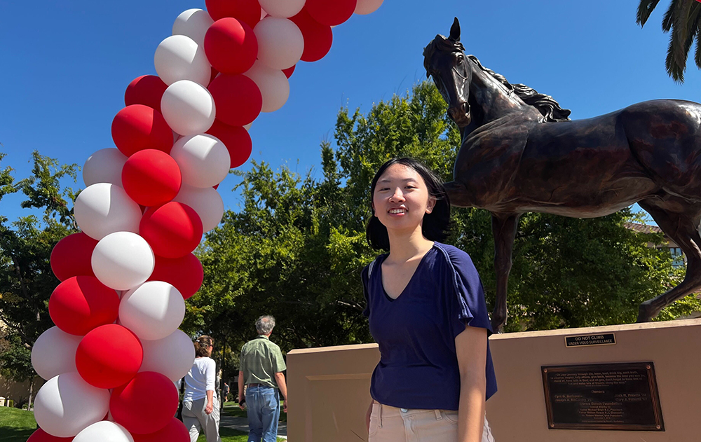 Emily Ramos standing in front of Bronco statue on campus with balloons on the left of the frame.
