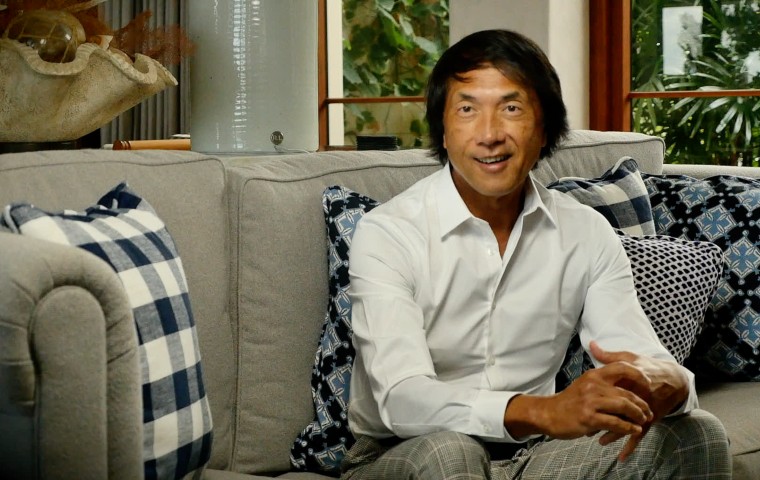 Photo of John Ocampo seated on a couch.