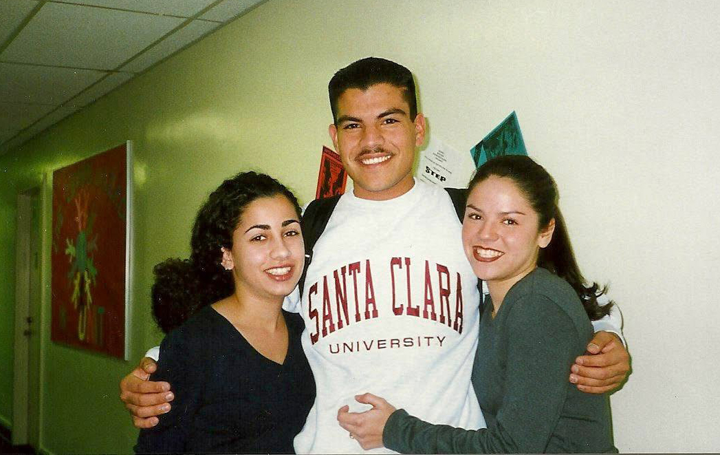 Jose Cabrales wearing Santa Clara sweatshirt, standing with two women classmates in residence hall hallway.