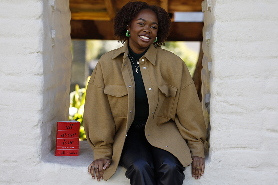 Kaylen Chase sitting on adobe wall with bell hooks' All About Love