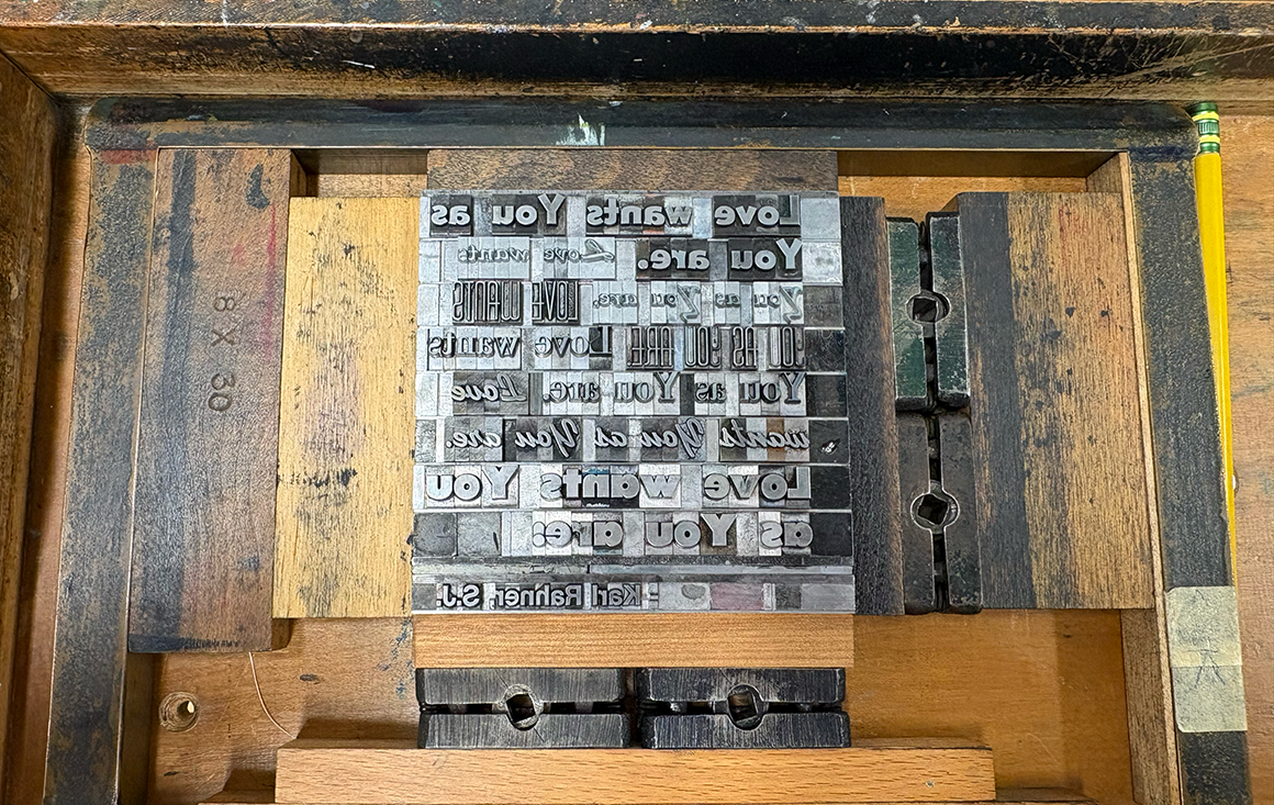 A set of metal types set in a letterpress, spelling out a message in reverse.