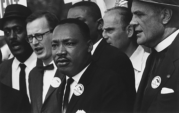 Martin Luther King Jr. speaks with a crowd behind him.