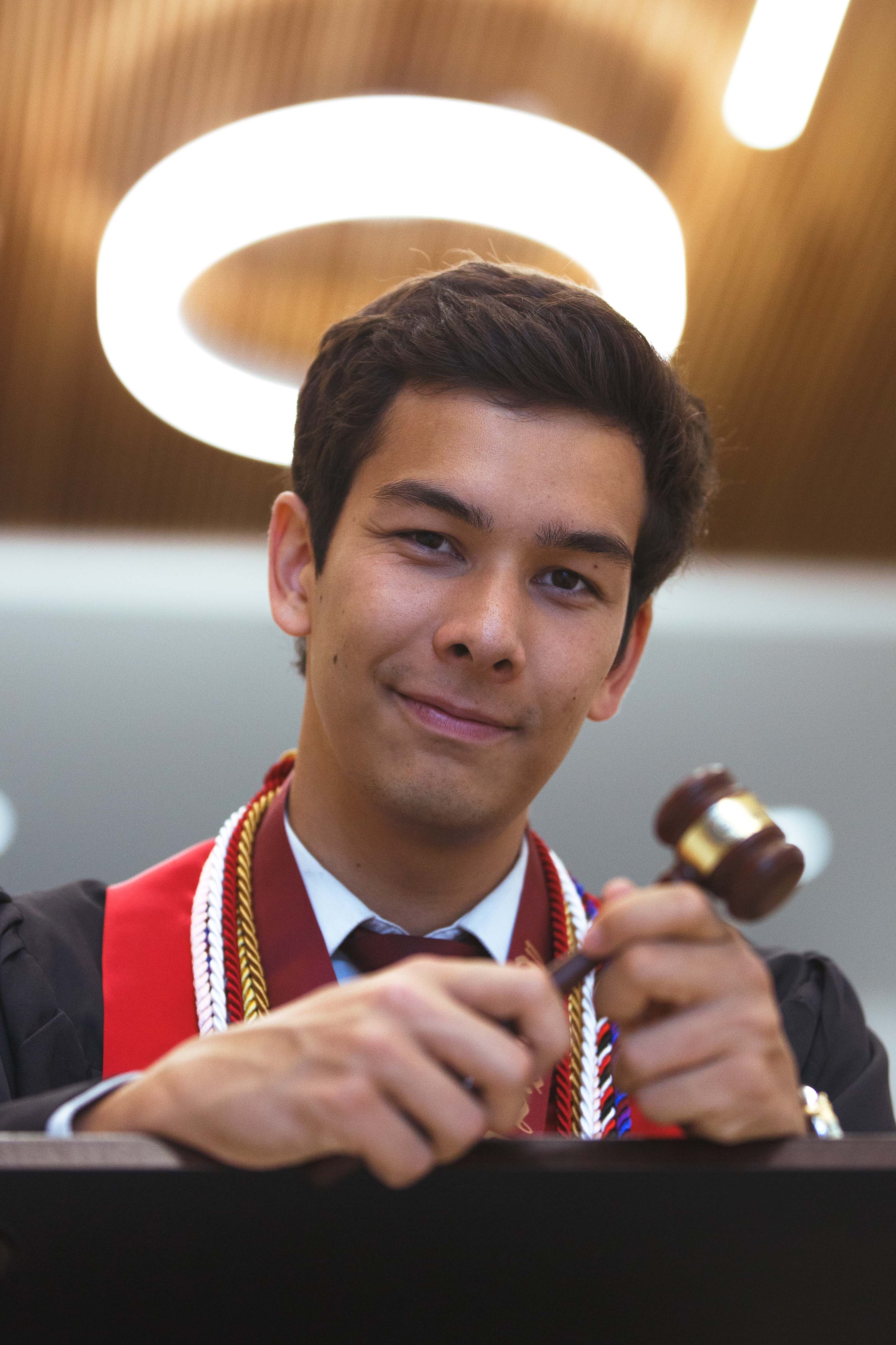 Man holds gavel wearing graduation garb.