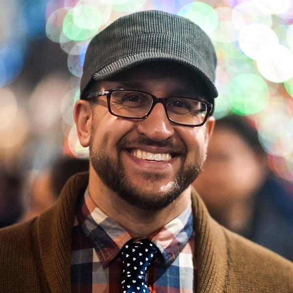 Paul Schutz wearing a hat and flannel shirt and tie.
