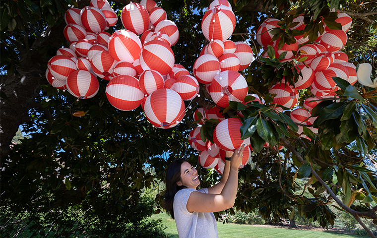 Caroline Wing '24 arranges paper lanterns she hung for an interactive exhibit at the Montalvo Arts Center.