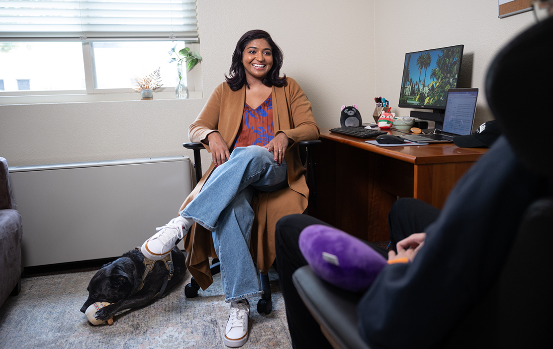 Photograph of Melba Mathew '12,  a therapist in residence at McLaughlin-Walsh, with her therapy dog Sam.