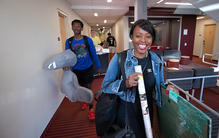 Two students walk suitcases into residence hall during move-in