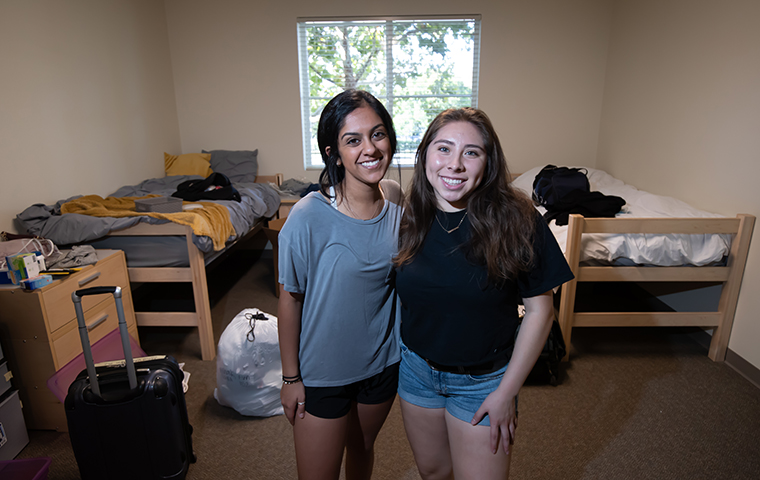 Two roommates stand in residence hall room