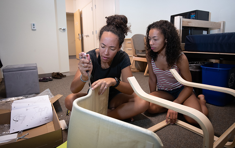 Two students put together furniture in residence hall room