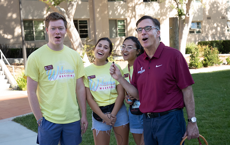 Fr. Kevin O'Brien and three students sing together during Welcome Weekend.
