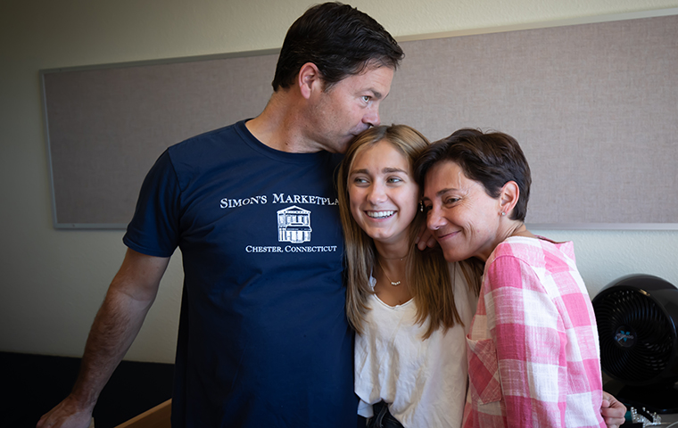 Father kisses daughter on head, mother hugs daughter during welcome weekend.