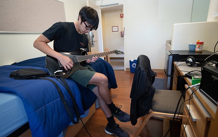 Student playing guitar in residence hall room